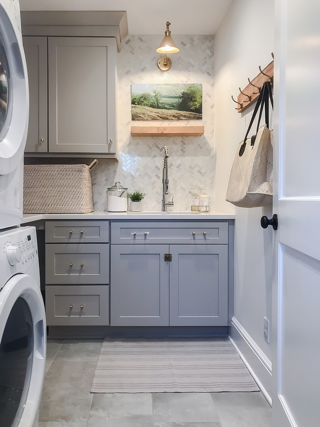 Grey Laundry room Grey cabinets works perfectly with the white marble quartz countertops and the white marble herringbone backsplash. Brass and acrylic hardware accentuates the shaker-style doors #greylaundryroom #greycabinet # greycabinets #marblequartz #countertop #marbleherringbonebacksplash #Brassandacrylichardware #shakerstyledoor