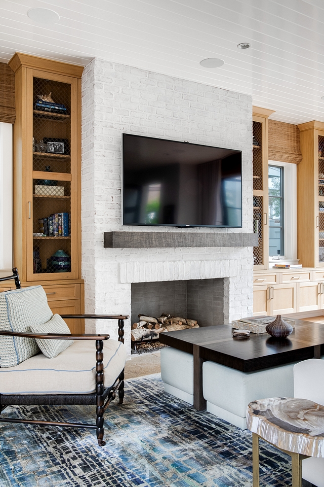 Living room features a stunning brick fireplace flanked by custom cabinets The cabinets are shaker style in rift white oak. Upper cabinets have wire mesh insert #Livingroom #brickfireplace #cabinets #shakerstylecabinet #Riftwhiteoak #wiremesh