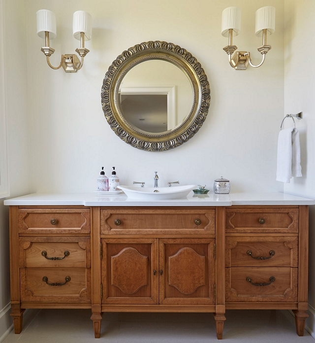 Furniture-like vanity cabinet This powder room features a beautiful furniture-like vanity cabinet with vessel sink, ornate mirror and matching sconces. Paint color is Sherwin Williams SW7014 Eider White in an Eggshell finish Furniture-like vanity cabinet #Furniturelikevanity #vanity #cabinet