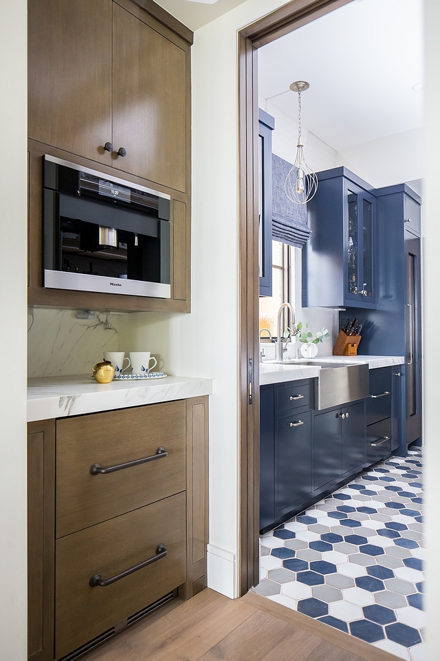 The kitchen leads to a coffee bar and fully-equipped pantry with navy blue cabinets in Benjamin Moore Hale Navy HC154 #pantry #kitchen #coffeebar #coffeebarcabinet #barcabinet #bar #navybluecabinet #BenjaminMooreHaleNavy #BenjaminMooreHC154