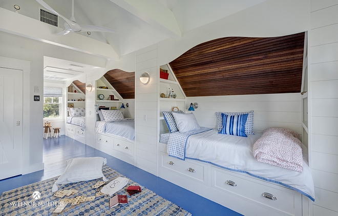 Low ceiling Bunk Room The built-in bunk beds features a shipshape style with mahogany ceilings, white shiplap side walls, and nautical bed linens and accents