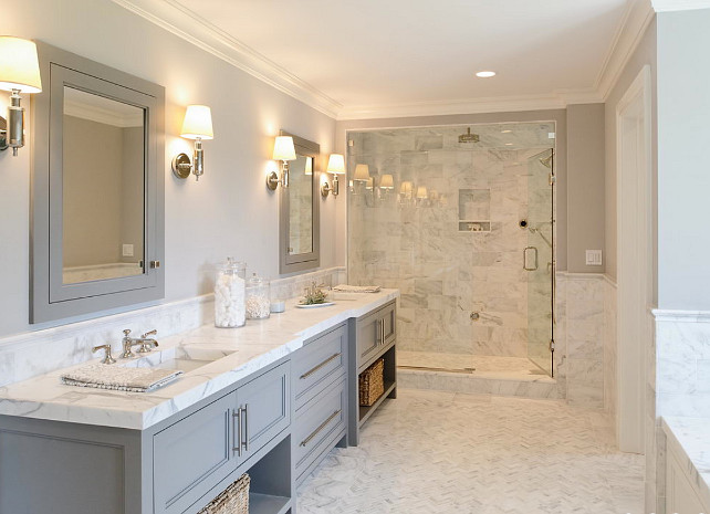 Gray Bathroom cabinet. Gray Bathroom cabinet paint color. Gray bathroom features gray double washstand paired with statuary marble countertop and his and her sinks and gray medicine cabinets over herringbone marble tiled floor. #Bathroom #Gray #Cabinet Blue Water Home Builders.