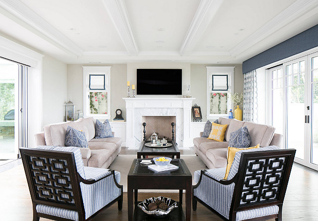Living Room. Coastal Living Room. Modern Coastal Living Room with fireplace. beams blue cushions blue pillows glass double doors glass wall gray couch gray sofa great room herringbone marble fireplace roller blinds sliding glass door television transom windows wood coffee table yellow pillows #CoastalLivingRoom
