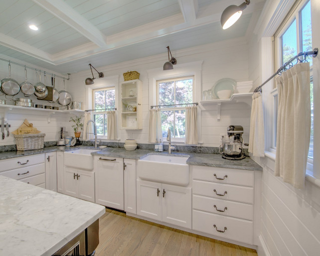 Two Farmhouse Sinks. Kitchen with Two Farmhouse Sinks. A touch of farmhouse! The kitchen features two farmhouse sinks, tongue and groove walls, open shelves, swing arm sconces, coffered ceiling with shiplap painted in light blue and a side window with lower half curtain in linen. #kitchen #Twofarmhousesinks #Kitchensinks