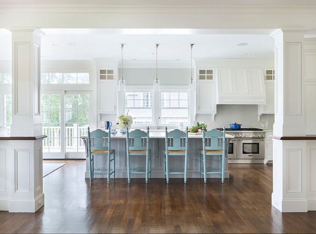 Turquoise Blue Kitchen Counter Stools. White and blue kitchen features three glass pendants illuminating a grey center island topped with white marble lined with turquoise blue counters tools with rush seats. #TurquoiseBlue #Kitchen #CounterStools Digs Design Company.