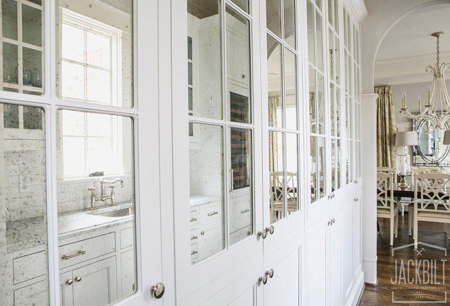 Antique Mirror Kitchen Cabinet. Kitchen boasts a wall of white pantry cabinets adorned with nickel knobs fitted with antiqued mirrored cabinet doors. #AntiqueMirror #Kitchen #Cabinet JackBilt Homes.