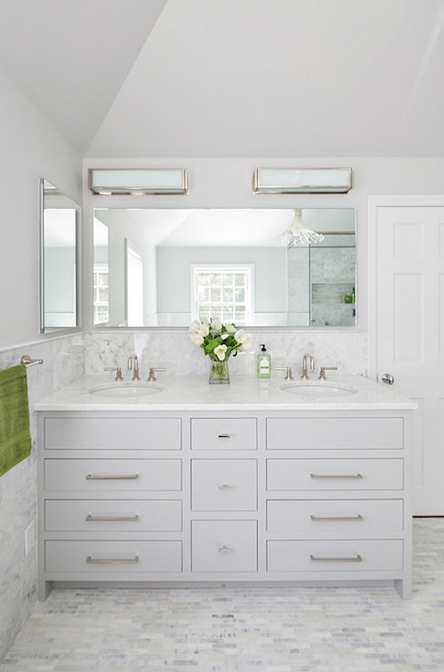 Bathroom Cabinet Ideas. White and gray bathroom features upper walls painted gray and lower walls clad in marble wainscoting finished with marble pencil tiles framing a light gray dual bathroom vanity topped with white marble framing round sinks under frameless full length vanity mirror lit by two long box sconces atop linear marble tiled floor adjacent to wall lined with inset frameless medicine cabinet. #bathroom Clean Design Partners 