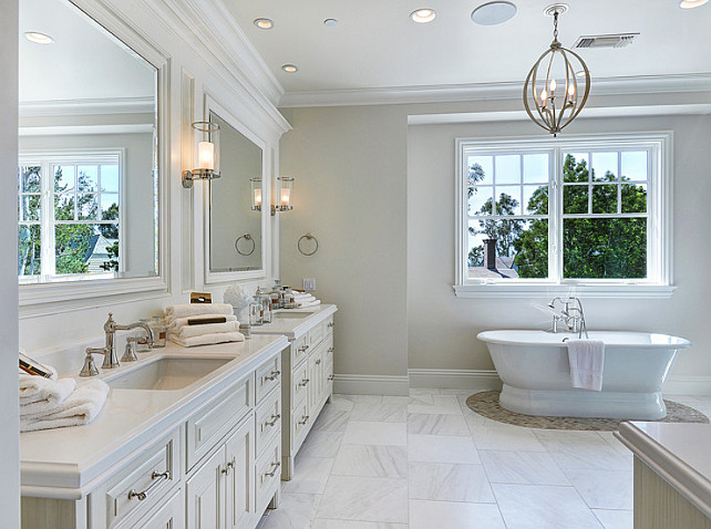 Bathroom. Neutral Bathroom Ideas. The master bathroom features custom his and hers vanity painted in an ivory color. The freestanding bath is framed by pebble flooring. #NeutralBathroom