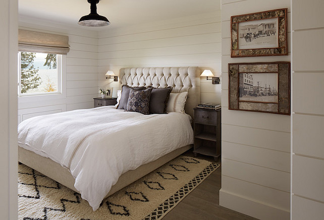 Bedroom with shiplap paneled walls over gray washed hardwood floors layered with a Moroccan style wool rug. Designed by Artistic Designs for Living.