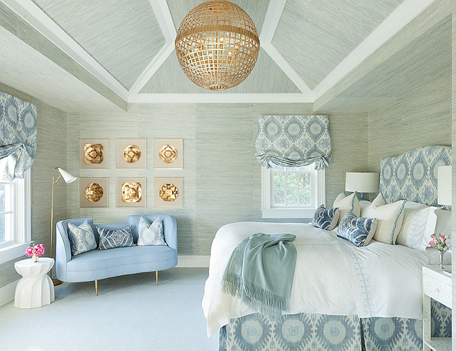 Blue and gray bedroom features walls and ceiling clad in gray grasscloth wallpaper lined with a blue ikat headboard and brass cage globe lantern. Anna Burke Interiors.