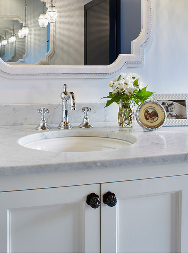 White bathroom vanity with Carrara marble countertop and the bathroom faucet is by Rohl. The bathroom cabinet is painted in BM White Dove. Martha O'Hara Interiors.
