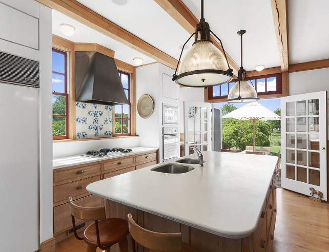 Charming Cottage Kitchen. Cottage Kitchen with traditional blue and white backsplash, aged white oak cabinets, exposed ceiling beams and industrial pendant lighting above island. #Kitchen #Cottage #CottageKitchen .