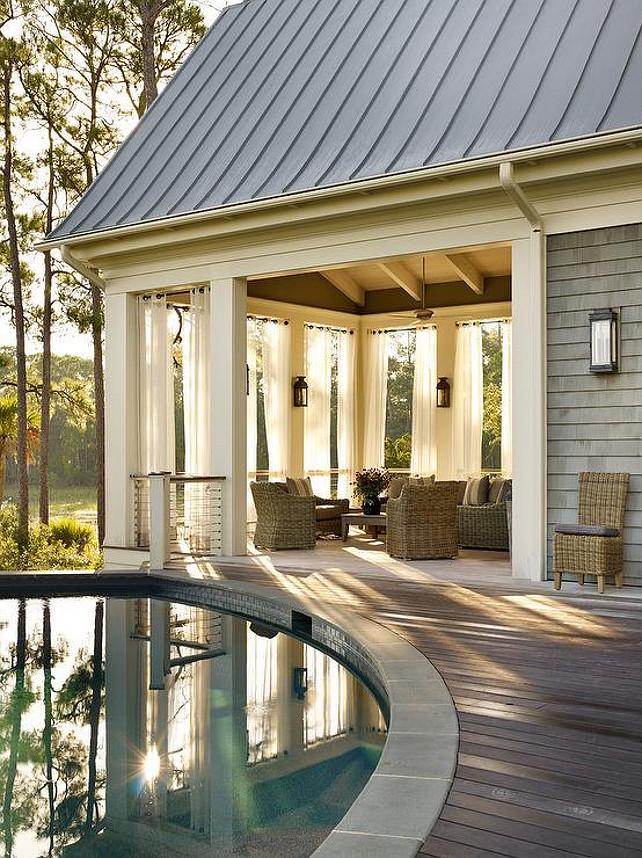 Circular Pool. Cottage home features a circular in-ground pool next to a covered deck filled with wicker furniture finished with white grommet outdoor drapes. Interior Design by Beth Webb Interiors.