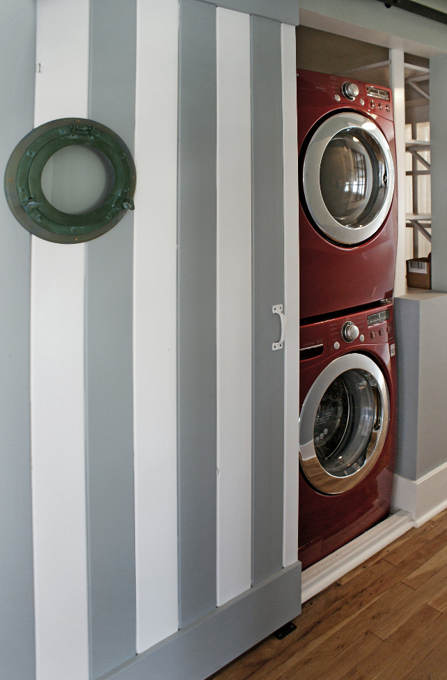 Closet Laundry Room. Closet Laundry room. This closet laundry room is located in the hallway and features a striped barn door painted in white and gray . A marine window adds coastal charm to this laundry room. #LaundryRoom #ClosetLaundryRoom #BarnDoor