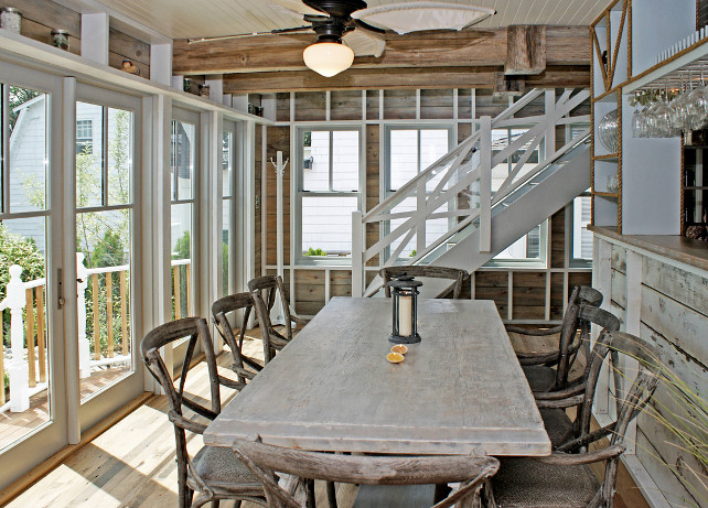 Dining Room. Coastal dining room with dining table. The weathered dining table with room for eight is positioned with large windows to let in maximum light. Beach cottage dining rooom. Beach home. Beach house dining room with bentwood dining chairs, ceiling fan, french doors, lanterns, natural light, reclaimed wood, rustic wood, wine glass storage, wood ceiling, wood floors, wood staircase, reclaimed wood walls. #DiningRoom OUTinDesign.