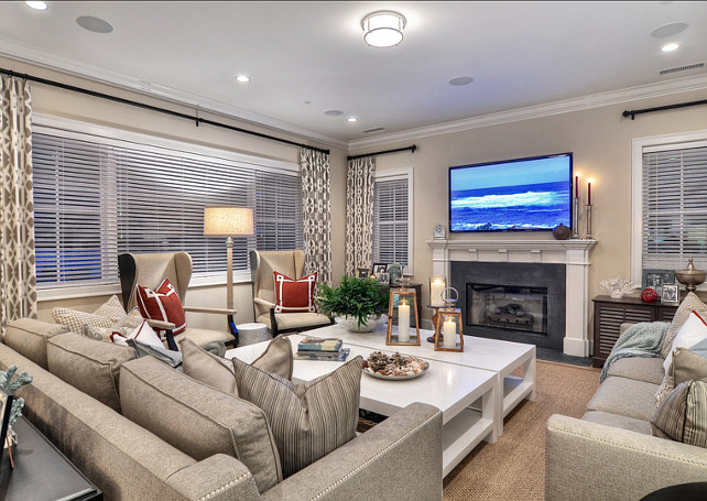 Family Room. Touches of nautical red and sea blue add color to this neutral family room. Tan couches with nail head trim surround two large white coffee tables. #FamilyRoom