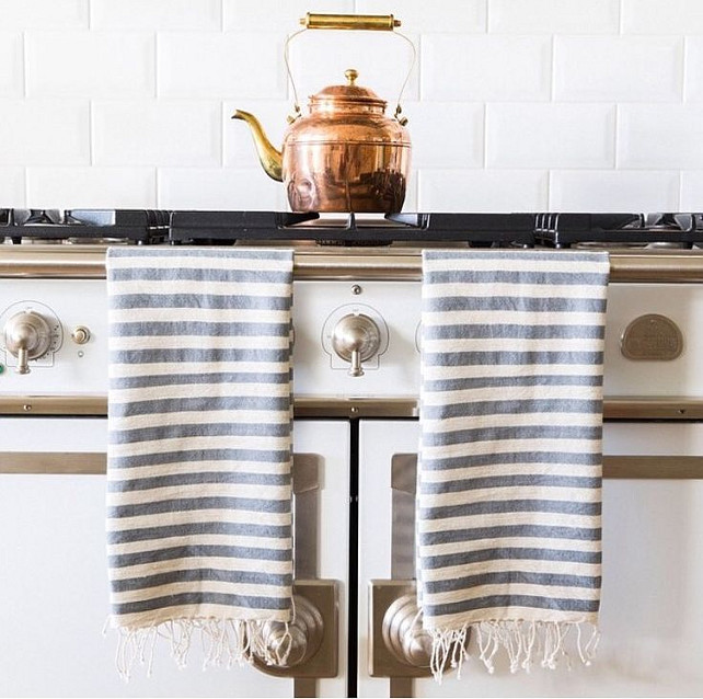 French Kitchen Ideas. French kitchen features a white French stove draped with white and gray striped Turkish towels under a subway tiled backsplash. #FrenchKitchen
