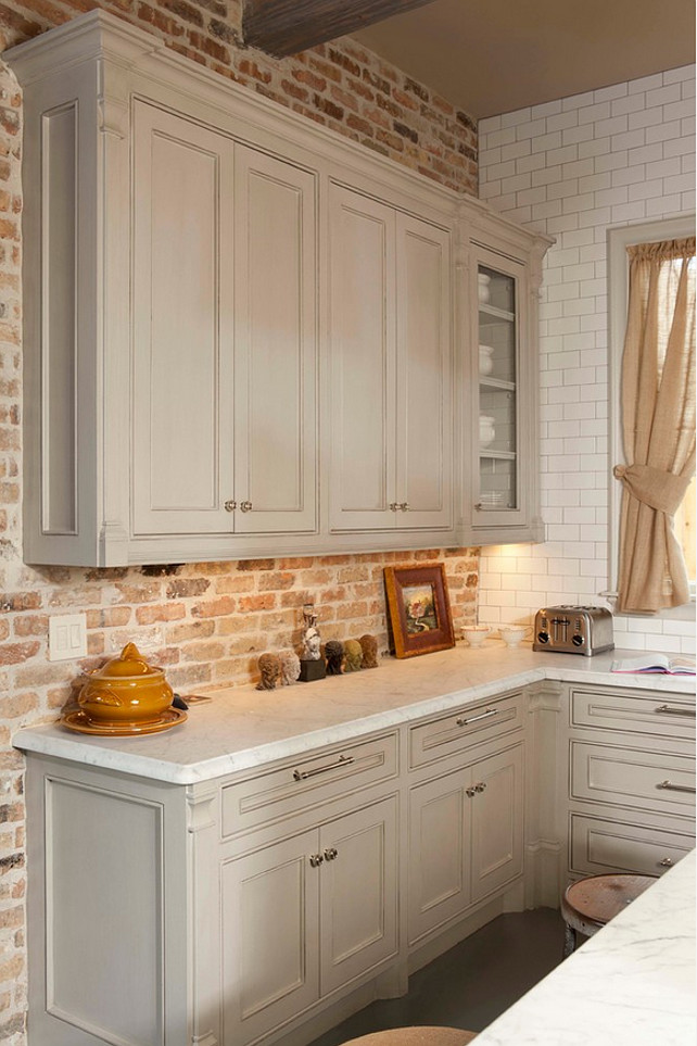 Gray Kitchen. Gray kitchen cabinet with brick backsplash wall and honed Carrara countertop. Whitestone Builders.