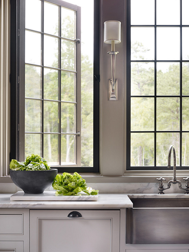 Gray Kitchen. Kitchen features gray cabinets paired with white marble countertops fitted with a stainless steel apron sink and deck-mount gooseneck faucet and Ruhlmann Single Sconces. #Kitchen #GrayKitchen Dungan Nequette