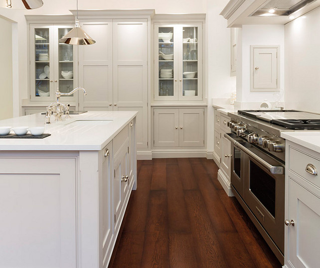 Kitchen Cabinet Ideas. Fabulous kitchen with light gray cabinets paired with white quartz countertops as well as light gray paneled hood over wolf Range. Kitchen features polished chrome pendants over light gray kitchen island with white quartz countertops and sink accented with vintage style faucet. Kitchen with built-in hutches flanking pantry cabinet. #Kitchen #KitchenCabinet Tom Howley