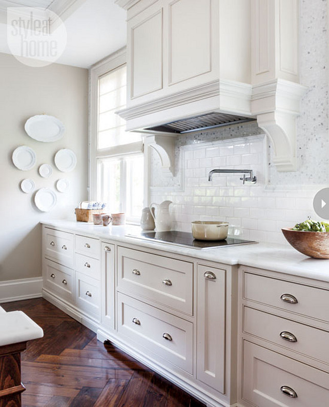 Kitchen Ideas. Kitchen with white cabinets, custom kitchen hood, white subway tiles, polished nickel pulls and reclaimed elm hardwood floors laid in a herringbone pattern. #kitchen Style at Home via Pintucks & Peonies.