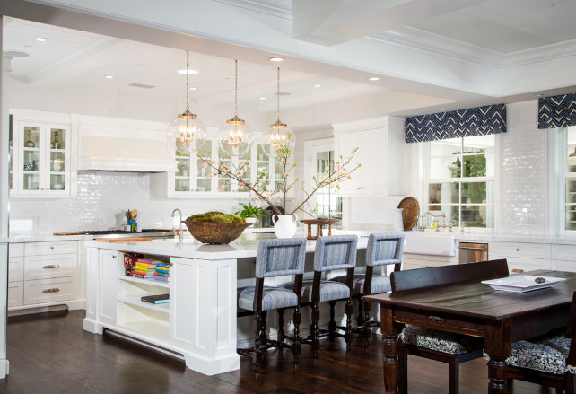 Kitchen layout. Open kitchen layout. Glass-front kitchen cabinets flank paneled range hood over glossy white mini subway tiled backsplash above stainless steel stove. #OpenKitchen #OpenKitchenLayout