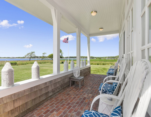 Porch Chair Ideas. Beach cottage porch with white chairs with cushions. Brick flooring porch. Beadboard ceiling porch. Porch Lanterns. American flag porch. #Porch