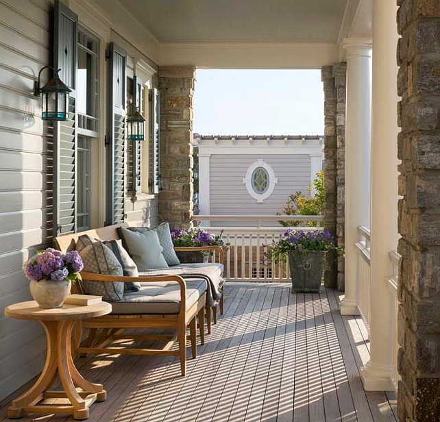 Porch. Front Porch. Front porch ceiling painted blue over windows dressed in gray shutters lined with an outdoor sofa facing stone piers and doric columns. #Porch #FrontPorch Robert A M Stern Architects