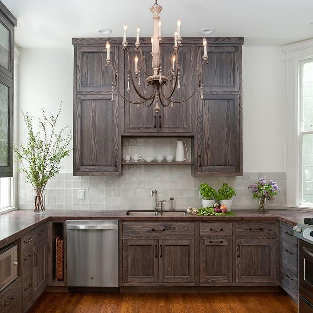 Small Kitchen. Small Kitchen with Burnt Oak Cabinets. Small kitchen features a French candle chandelier illuminating dark stained cabinets paired with a dark stained wood countertop and a gray tiled backsplash. #SmallKitchen #Kitchen #BurntOak #BurntOakCabinet K G Bell
