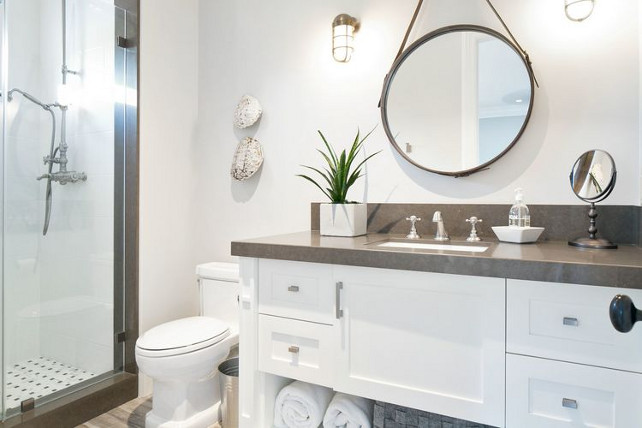 Transitional Bathroom. This transitional bathroom features leather captain's mirror illuminated by nautical sconces. The washstand is topped with gray quartz countertop. Kelly Nutt Design.