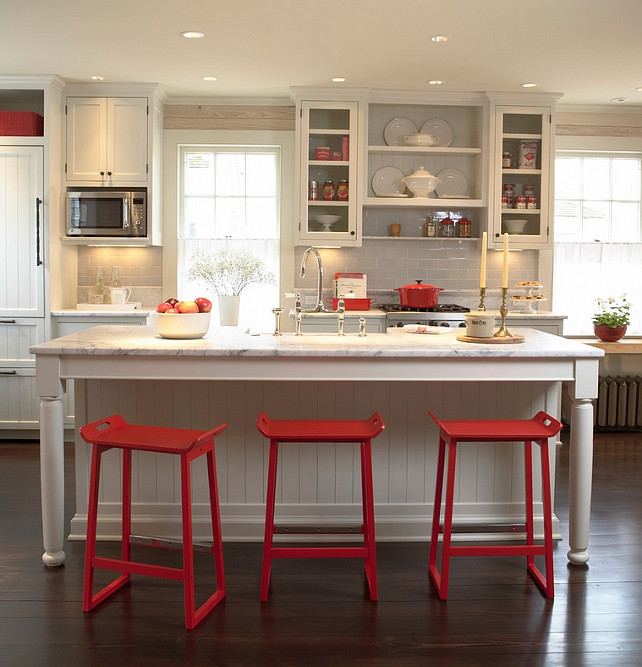 White Kitchen with pops of red. White kitchen with red decor. White Kitchen with red counterstools and decor. The subway tile backsplash is Waterworks Architectonics 3x6 in Dove. White Kitchen and red. #WhiteKitchen Meriwether Inc.