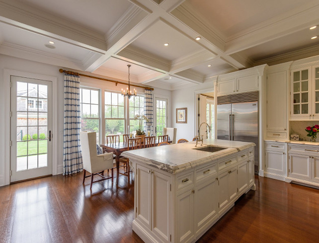 Kitchen. White Kitchen. Classic white kitchen with white kitchen island, coffered ceiling, polished nickel pull hardware, traditional kitchen cabinet, kitchen with hardwood floors, kitchen island with marble countertop with 1 1/2" Ogee Bullnose edge. Kitchen opens to breakfast nook with windows and door to patio. Coffered ceiling always add so much to a room and it specially brings this kitchen to a more sophisticated size. The kitchen island features 1 1/2" Ogee Bullnose edge. Notice that the island was kept without pendants to keep it simple and "clean". #Kitchen Via Sotheby's Homes.