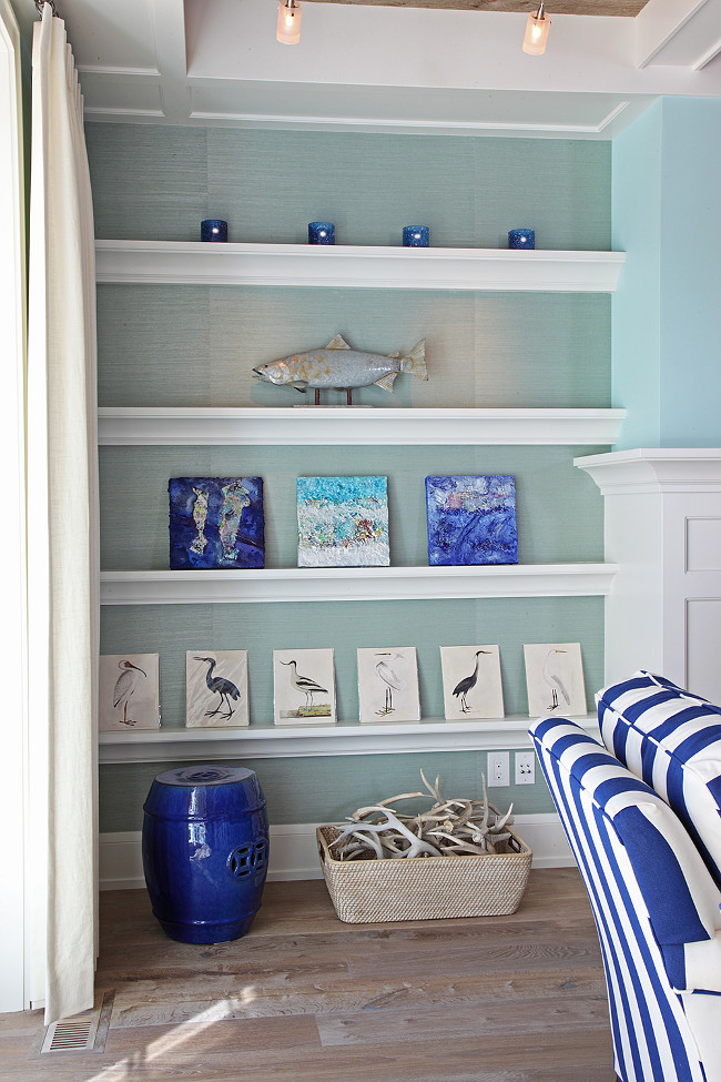 Coastal Living room with Coastal Art in fireplace bookcase. Fireplace bookcase features a turquoise wallpaper on the back wall. Leticia Little.