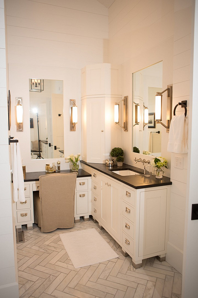 Corner Bathroom Cabinet. Corner Bathroom Cabinet Layout. Master bathroom features a white vanity topped with soapstone under an inset mirror illuminated by Eclipse Wall Lights next to a corner cabinet and a drop down make up vanity paired with a natural linen slipcovered chair atop a marble herringbone floor. #CornerBathroomCabinet Hahn Builders.