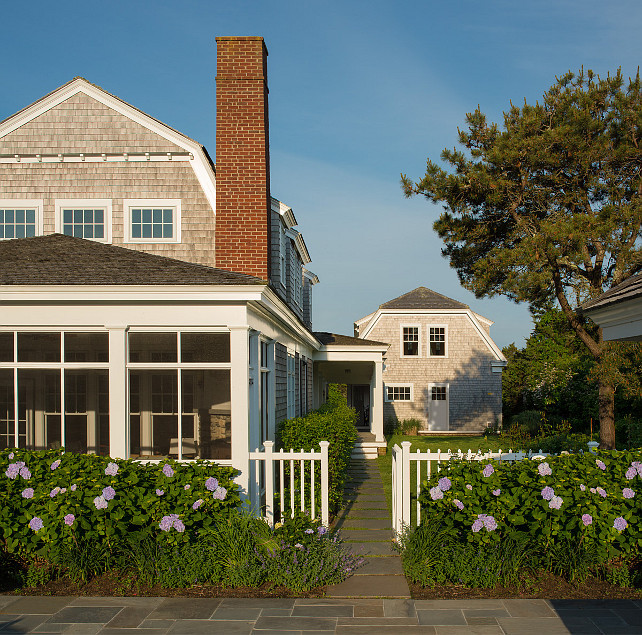 Screen Porch. Clipped gable roof. Gambrel roof. Paved sidewalk. Red brick chimney. Screened in Porch. Spaced pavers. Weathered wood shingles white door. White fascia. White picket fence. Cedar Shingle Weathering.