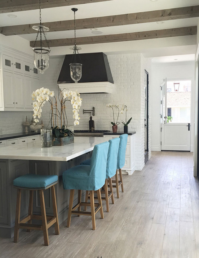 Bright White Kitchen with plank hardwood floors. Bright White Kitchen with plank hardwood floors, marble counters, white brick walls, beamed ceiling and turqupise stools. #Kitchen #BrightWhiteKitchen #WhiteKitchen Blackband Design.