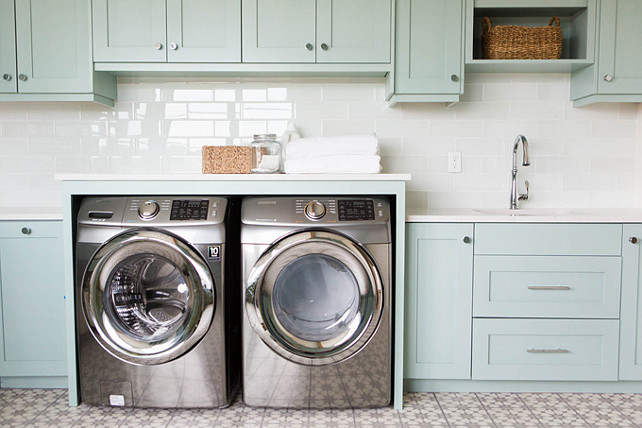 Laundry Room Backsplash. Laundry Room Tile Backsplash. Laundry Room Tile Backsplash Ideas. Fantastic laundry room with Wythe Blue cabinets paired with white quartz countertops and a white glass subway tiles backsplash. An enclosed washer and dryer stands under cabinets next to a stainless steel sink and gooseneck faucet alongside a white and gray mosaic tiled floor. Ashley Winn Design.