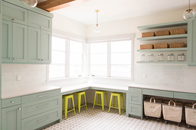 green cabinets gray green cabinets gray green shaker cabinets green laundry room cabinets gray green shaker laundry room cabinets green laundry room cabinets green shaker cabinets white quartz countertop white glass tiles white glass subway tiles white glass backsplash white glass laundry room backsplash vintage laundry room carts green shelves green floating shelves green laundry room shelves laundry room desk corner desk corner laundry room desk yellow stools yellow tolix stools desk under window corner built in desk. This laundry room is perfect! Notice the fitted L shaped corner desk lined with yellow Tolix Stools placed below the windows. This area is great for folding or crafts.