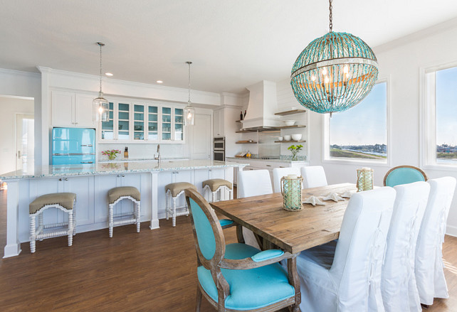White and Turquoise Kitchen. This white and turquoise kitchen features a pair of Corsica Pendants illuminating an extra-long center island with legs fitted with recycled glass countertops framing sink and satin nickel gooseneck faucet lined with Noir Abacus Counter Stools. #Kitchen #WhiteKitchen #Turquoise #TurquoiseKitchen Laura U, Inc. 