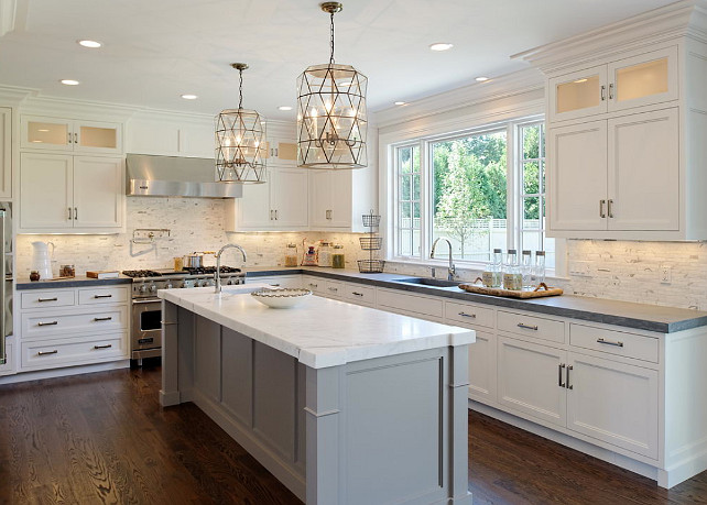 Kitchen Design. Gorgeous kitchen with white perimeter cabinets paired with honed black countertops and white marble backsplash. Worlds Away Mariah Pendants over gray kitchen island with white marble countertop with prep sink accented with gooseneck faucet. #Kitchen #Design #KItchenDesign Blue Water Home Builders.