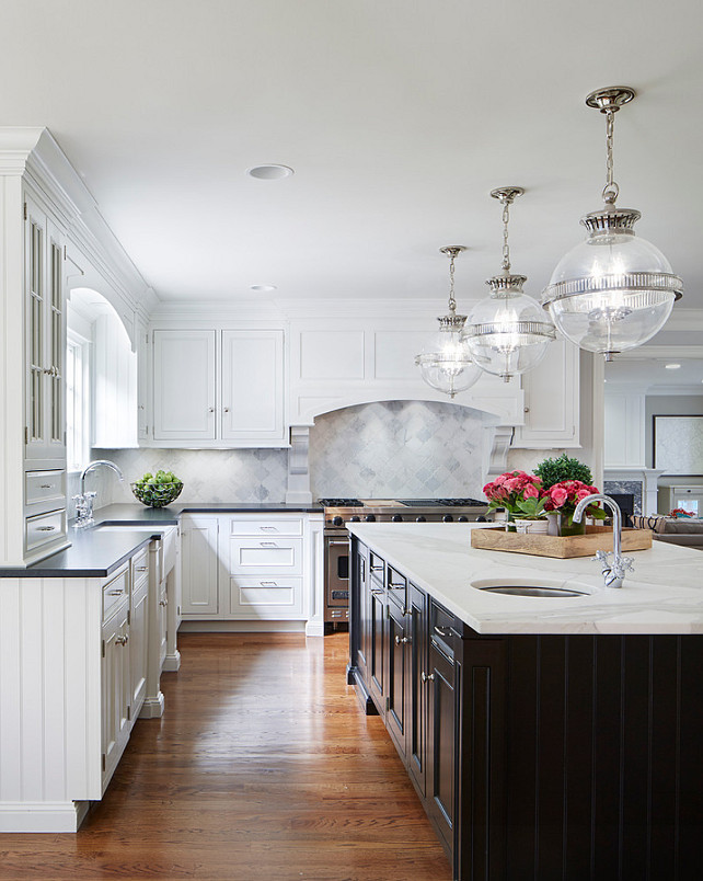 White Kitchen with Espresso Island. The Island Countertop is a Calacatta Marble, the Perimeter Countertop is a Soapstone and the Backsplash Tile was done in a Arabesque Carrara Marble Tile. White Kitchen Cabinet with Espresso Stained Island. White Kitchen Perimeter Cabinet with Espresso Island. The pendants above the island are the E.F. Chapman Alderly Globe Pendant. #WhiteKitchen #EspressoIsland #Kitchen #KitchenIsland Martha O'Hara Interiors.