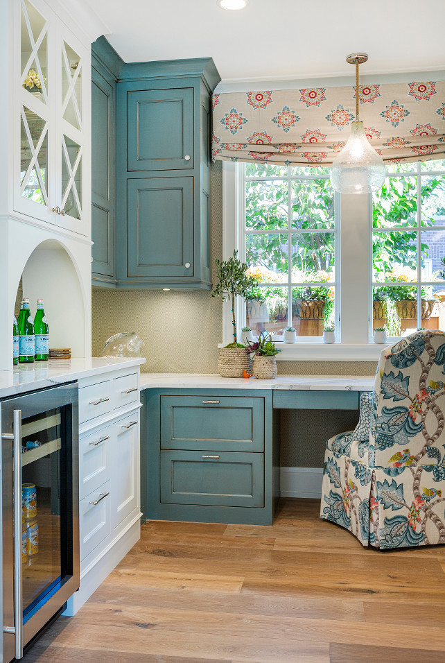 Kitchen Desk. Kitchen Desk Area. Kitchen Desk and kitchen bar. The window treatment is from Cowtan & Tout. Desk pendant lighting is from Creative Lighting. Kitchen Desk with blue cabinets and herringbone linen wallpaper. Kitchen desk with slipcovered chairs. #Kitchen #Desk #KitchenDesk Great Neighborhood Homes.