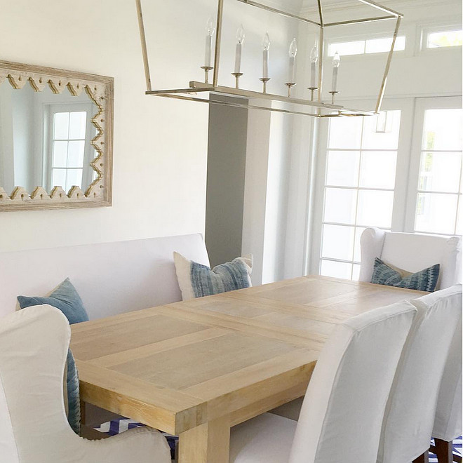 Dining Room. Neutral dining room Coastal white and blue dining room with Darlana Linear Chandelier, white slipcovered chairs and denim pillows by JP Cajuste Pillows. Table is made by Sarri #DiningRoom Rita Chan Interiors.