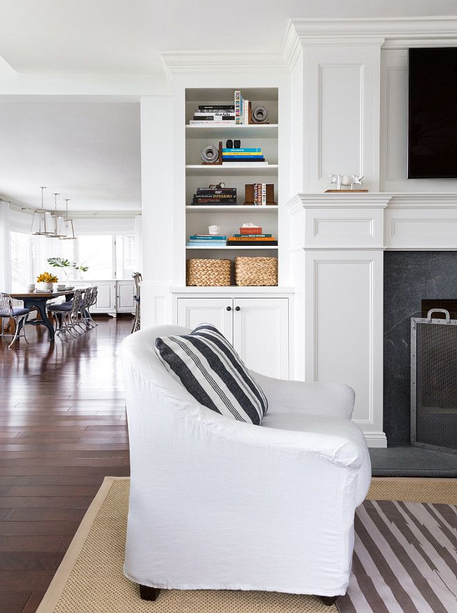 Beautiful fireplace with soapstone surround. The cabinet is painted in White Dove by Benjamin Moore. A swhite slipcovered chair features a dark gray striped pillow is from Ralf Lauren Home. Fireplace screen is from Pottery Barn. #Livingroom #Fireplace #Cabinet #Chair