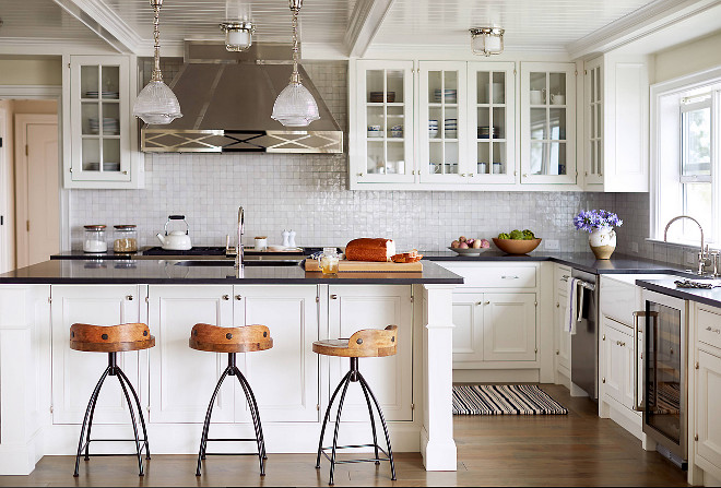 Coastal Kitchen. White Coastal Kitchen. White Coastal Kitchen. White Coastal Kitchen with stainless steel hood, Watermark kitchen faucets on island and perimeter countertop. Countertop is Black honed granite. Kitchen lighting from Circa Lighting. Kitchen backsplash is 2x2 squares glazed tiles to look like mother of pearl from reclaimed bricks. #kitchen #coastalkitchen Andrew Howard Interior Design.