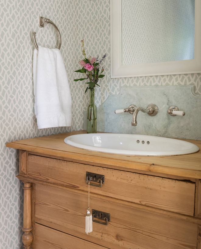 Cottage Bathroom. Neutral cottage bathroom featuring white framed wall mirror, towel ring, light turquoise trellis wallpaper, wall mounted faucet and a reclaimed dresser used as vanity. #Bathroom #Cottage #CottageBathroom 