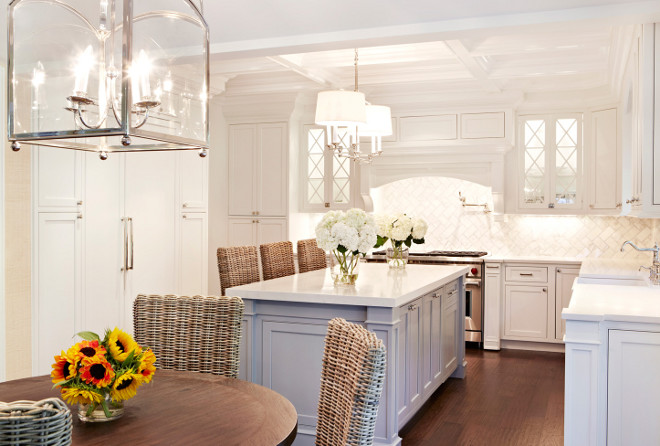 White kitchen with gray island featuring rattan chairs and rattan barstools from Restoration Hardware. Kitchen Cabinet paint color is Benjamin Moore Frostine AF-5. #whiteandgraykitchen #rattanchair #rattanbarstool #RestorationHardware #BenjaminMooreFrostineAF5. Chango & Co.