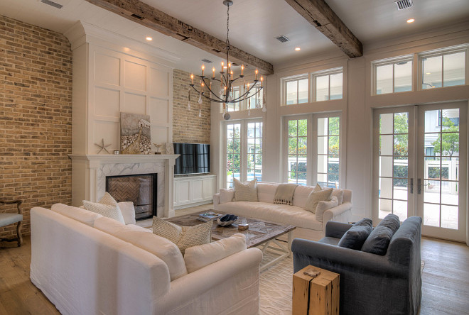 Living room with fireplace, reclaimed brick wall, reclaimed wood beams, bleached wide plank floors and French doors with transoms. #livingroom