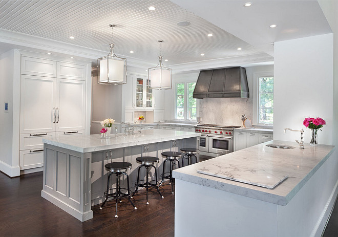 Kitchen with crisp white cabinets, zinc hood, gray island with marble countertop and separate peninsula with prep sink. Nahra Design Group