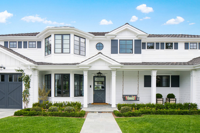 Home Exterior barn door batten shutters bay windows beach house blue accents blue trim front porch hedges landscaping porch swing shingle roof square column posts stable door traditional beach style two story home white house #Homeexterior Legacy CDM Inc.